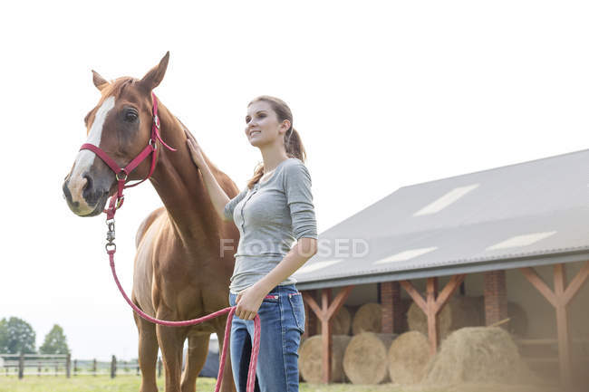 Smiling woman with horse outside rural barn — Stock Photo