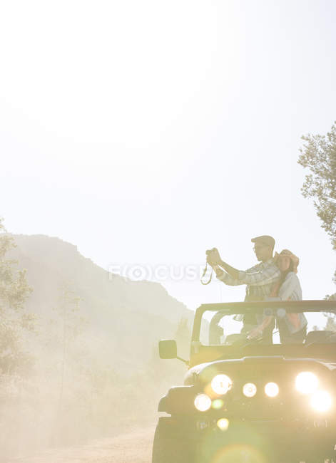 Couple with digital camera in sport utility vehicle — Stock Photo