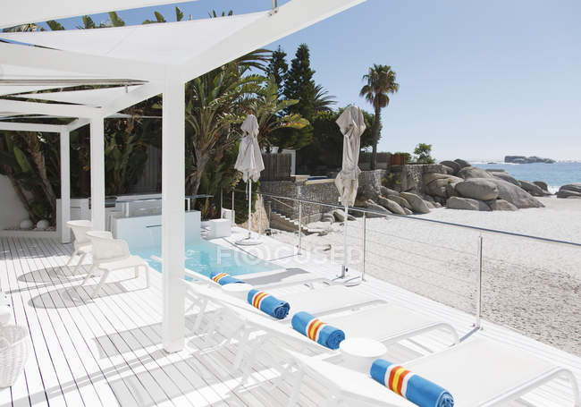 Cadeiras de estar e piscina com vista para a praia e o oceano — Fotografia de Stock