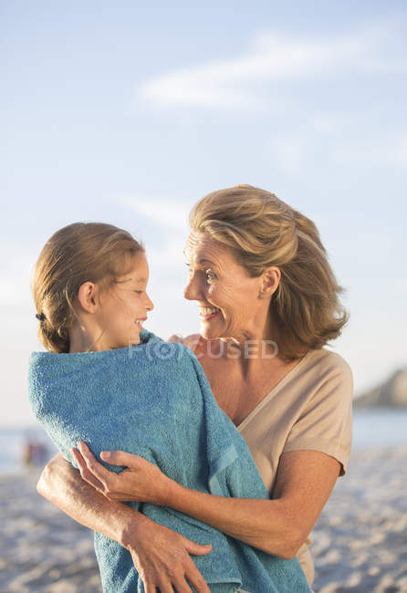 Older woman holding granddaughter on beach — Stock Photo