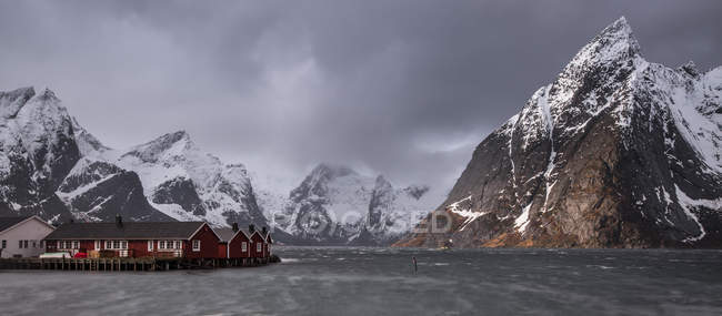 Catena montuosa innevata sopra il villaggio di pescatori, Hamnoya, Isole Lofoten, Norvegia — Foto stock
