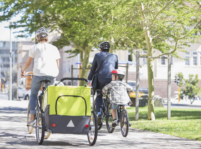 Familias montando bicicletas en el soleado parque urbano - foto de stock