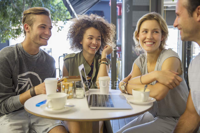 Friends hanging out with laptop and coffee on cafe patio — Stock Photo