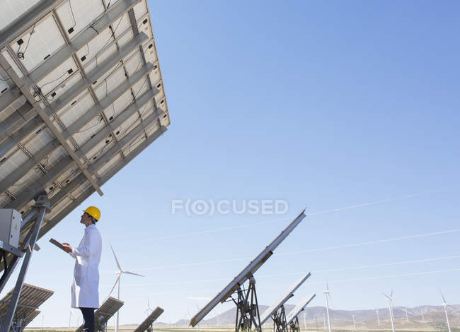 Scientist examining solar panel in rural landscape — Stock Photo