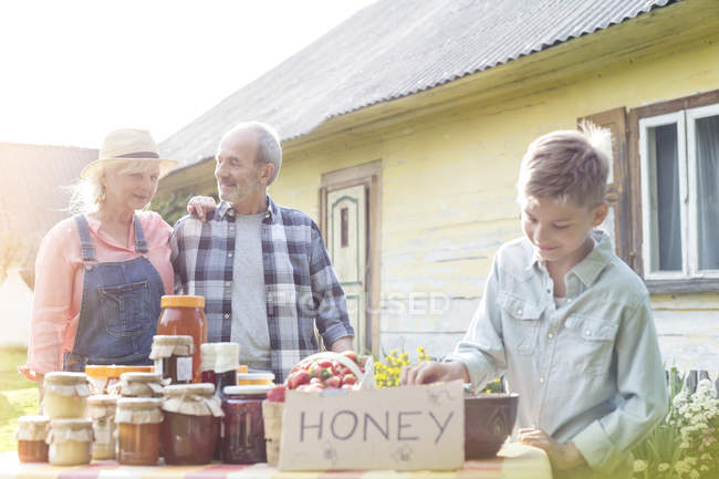 Grandparents and grandson selling honey — Stock Photo