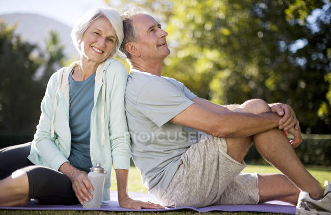 Couple âgé assis sur tapis de yoga dans le parc — Photo de stock