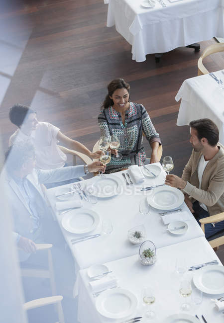 Freunde stoßen am Restauranttisch auf Weingläser an — Stockfoto