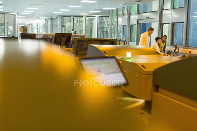 Trabalhadores no computador atrás de impressoras em fábrica de impressão — Fotografia de Stock