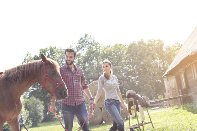 Couple à pied cheval à l'extérieur de la grange rurale — Photo de stock