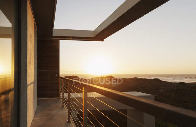 Балкон современного дома с видом на океан на закате — стоковое фото