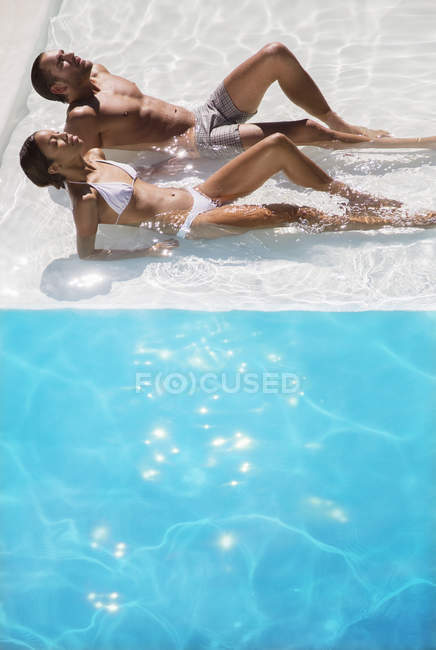 Jovem casal banhos de sol na piscina — Fotografia de Stock