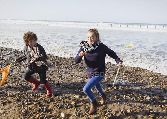 Irmão e irmã com redes correndo do oceano para a praia — Fotografia de Stock