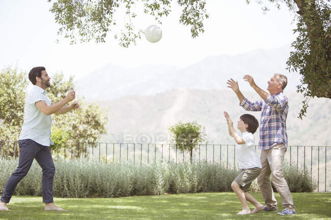 Multi-generation family playing volleyball in backyard — Stock Photo