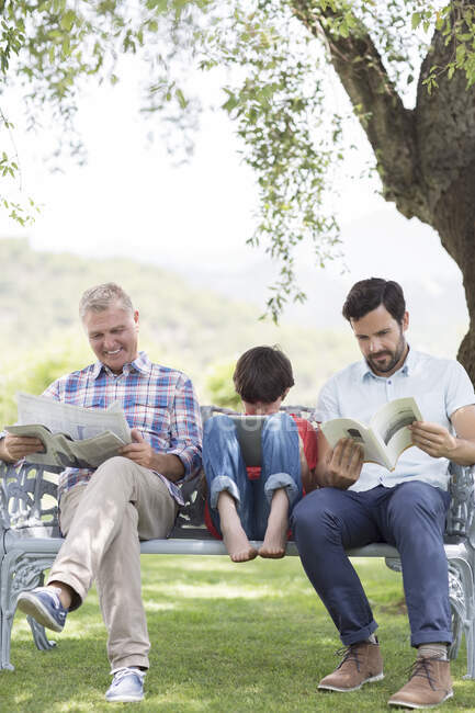 Multi-generation men reading on bench — Stock Photo