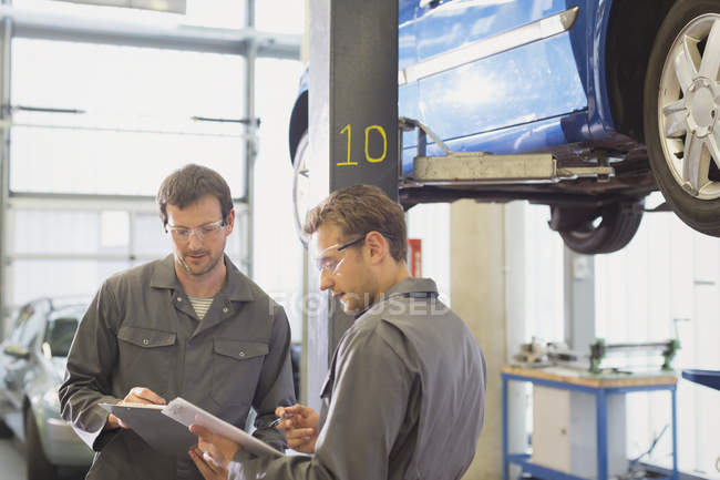 Mechanics reviewing paperwork in auto repair shop — Stock Photo