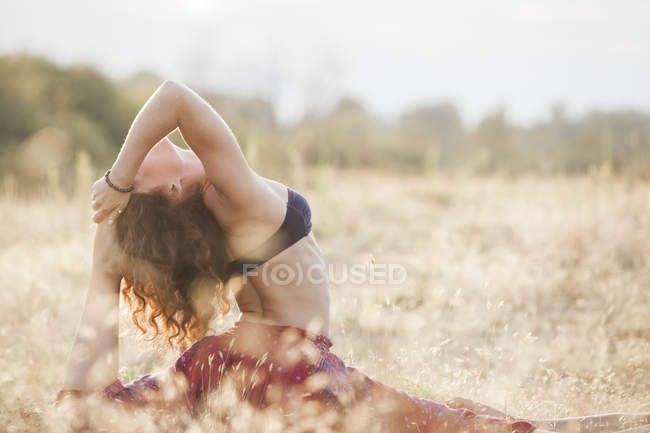 Mujer en real rey paloma yoga pose en campo rural - foto de stock