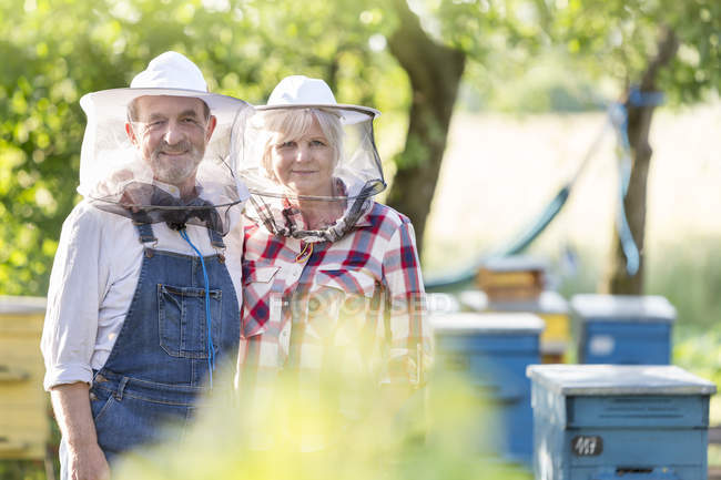 Портрет уверенных пчеловодов в защитных шляпах возле ульев — стоковое фото