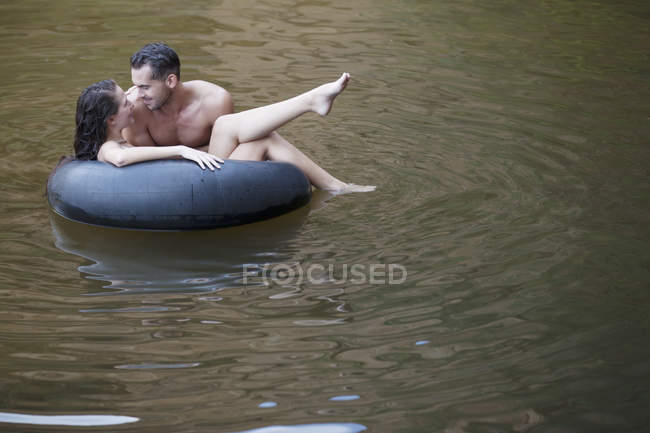 Couple playing in inner tube in river — Stock Photo