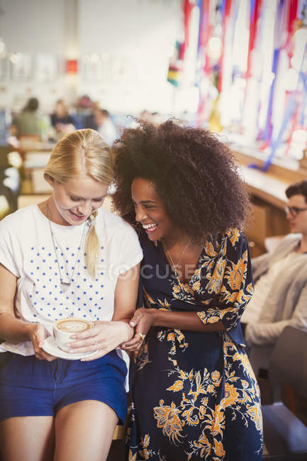 Friends laughing and drinking cappuccino in cafe — Stock Photo