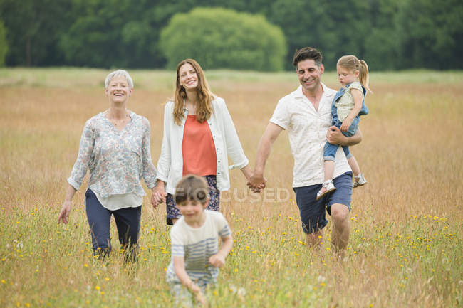 Família de várias gerações de mãos dadas e caminhadas no campo rural — Fotografia de Stock