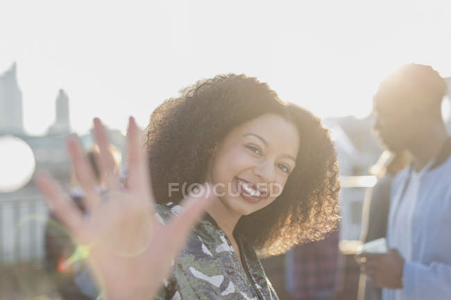 Portrait smiling woman waving at rooftop party — Stock Photo
