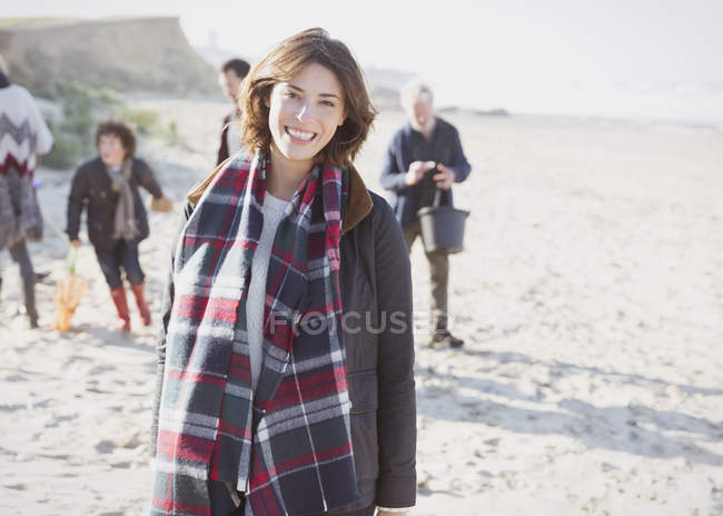 Retrato mujer sonriente en bufanda a cuadros con la familia en la playa - foto de stock