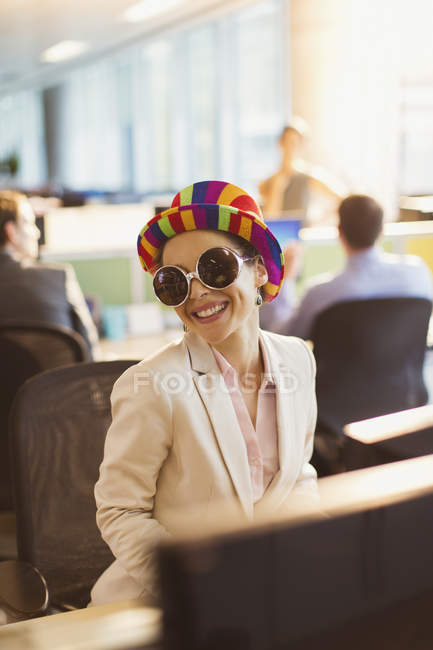 Retrato de mulher de negócios sorridente em óculos de sol bobos e chapéu listrado trabalhando no escritório — Fotografia de Stock