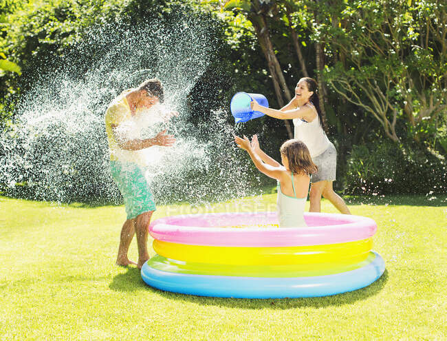 Family tossing water on father in backyard — Stock Photo