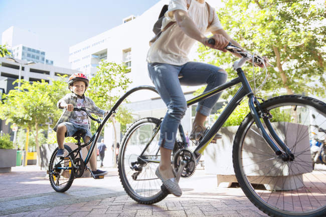 Hijo en casco montado en bicicleta tándem con madre en parque urbano - foto de stock
