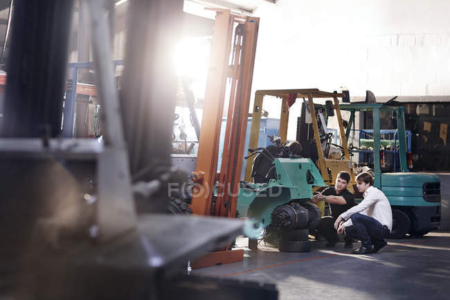 Mechanics fixing forklift in auto repair shop — Stock Photo