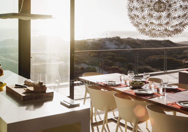 Modern dining room overlooking ocean at sunset — Stock Photo