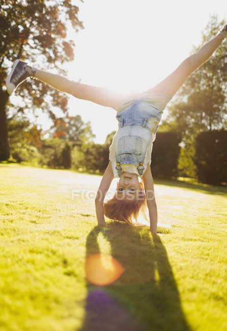 Chica haciendo handstand en soleado jardín - foto de stock