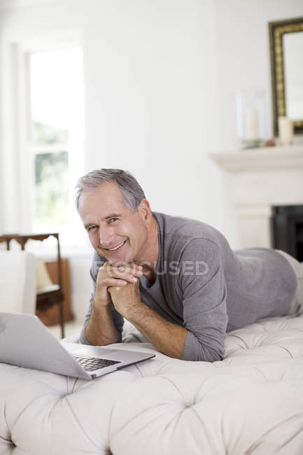 Homem sênior usando laptop na sala de estar — Fotografia de Stock