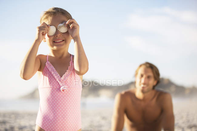 Девушка играет с ракушками на пляже — стоковое фото