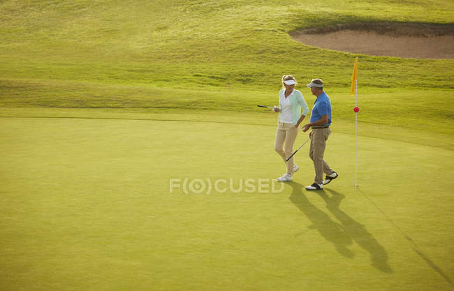 Senior couple walking on golf course — Stock Photo