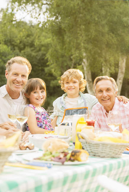 Multi-generation family eating lunch at table in backyard — Stock Photo