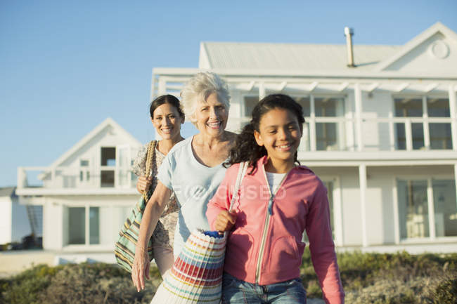 Multi-generación de mujeres caminando en el camino de la playa fuera de casa - foto de stock