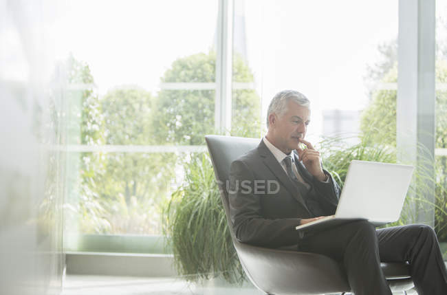 Empresário usando laptop no lobby — Fotografia de Stock