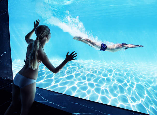 Femme regardant petit ami sous l'eau dans la piscine — Photo de stock