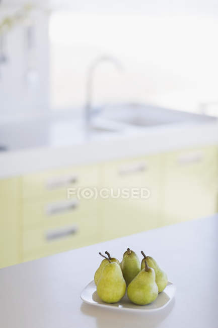 Тарелка свежих груш на кухонном столе — стоковое фото