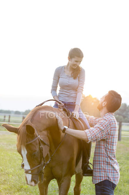 Sorrindo casal cavalgando em pasto rural — Fotografia de Stock
