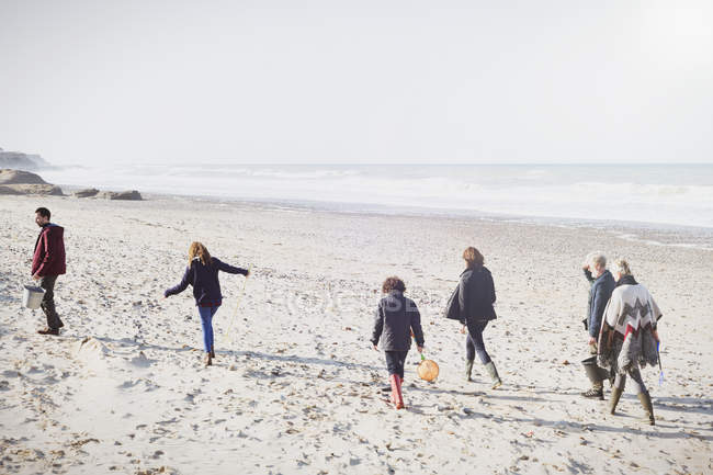 Famille multi-génération marchant sur une plage ensoleillée — Photo de stock