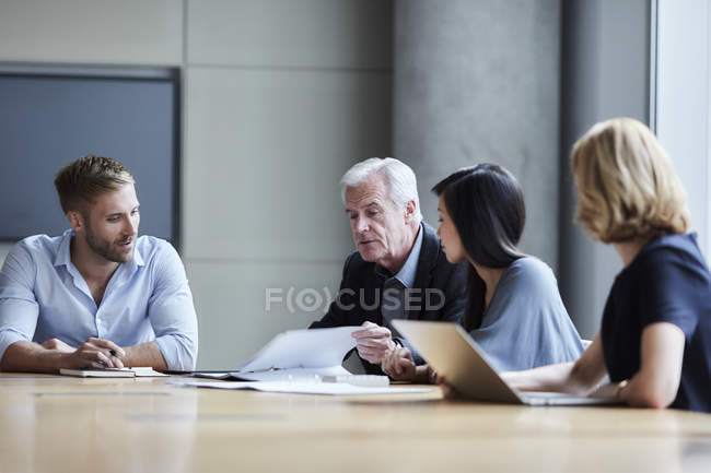 Empresários discutindo papelada na sala de conferências — Fotografia de Stock