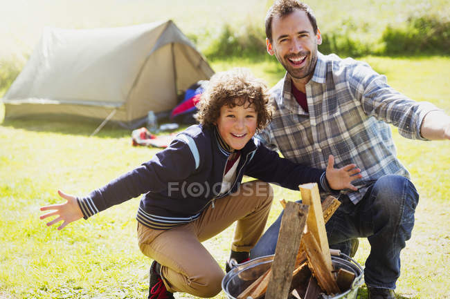 Portrait enthousiaste père et fils construisant feu de camp — Photo de stock