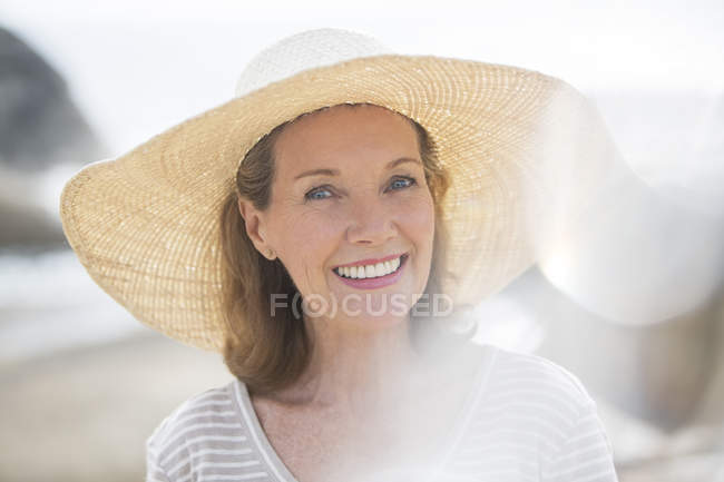Mulher mais velha usando chapéu de palha na praia — Fotografia de Stock