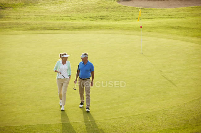 Couple sénior marchant sur le terrain de golf — Photo de stock