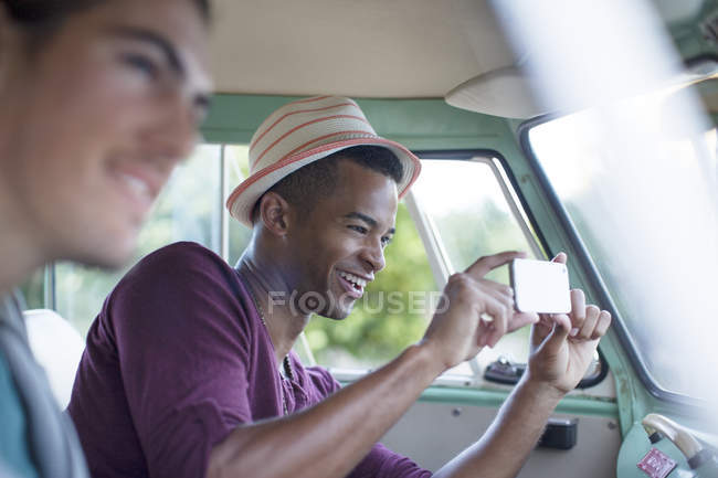 Man using camera phone in camper van — Stock Photo