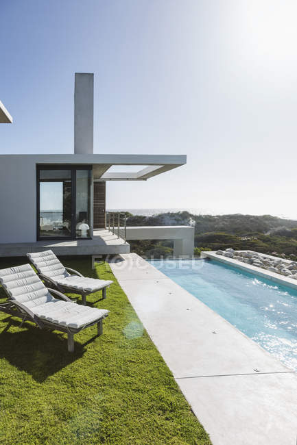 Liegestühle und Pool außerhalb des modernen Hauses — Stockfoto