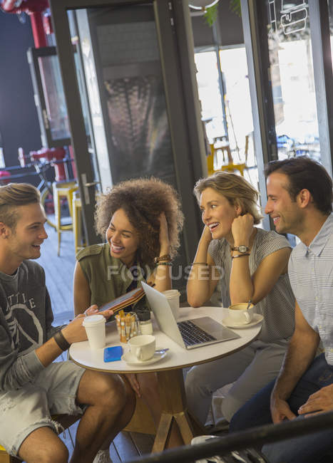 Amigos con tableta digital y portátil pasando el rato en la cafetería - foto de stock