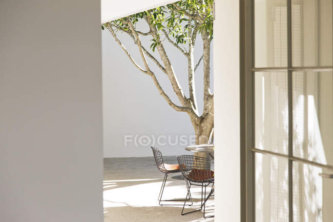 Table, chairs and tree in courtyard — Stock Photo